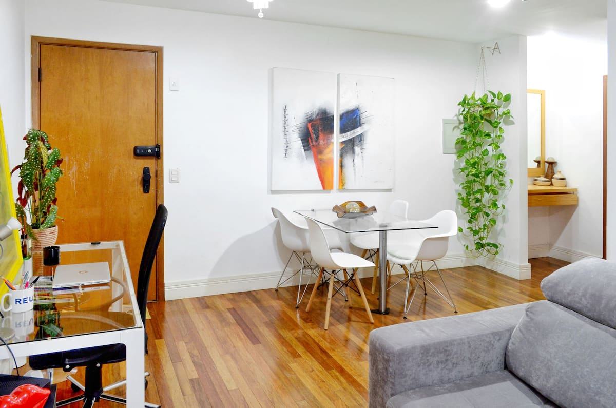 Sala de estar com sofá, mesa de jantar e piso de madeira