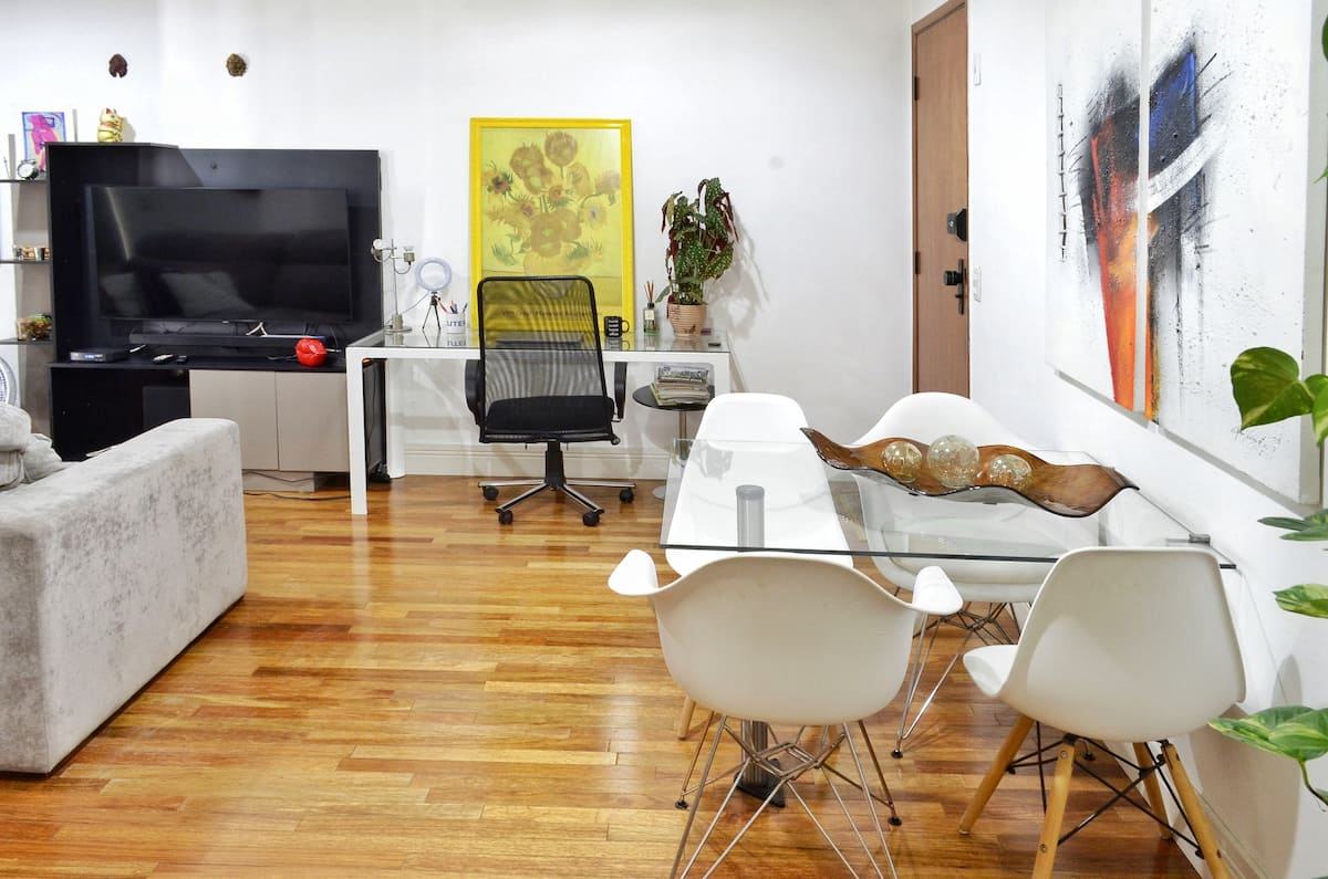 Sala com Smart TV, mesa de trabalho e mesa de jantar